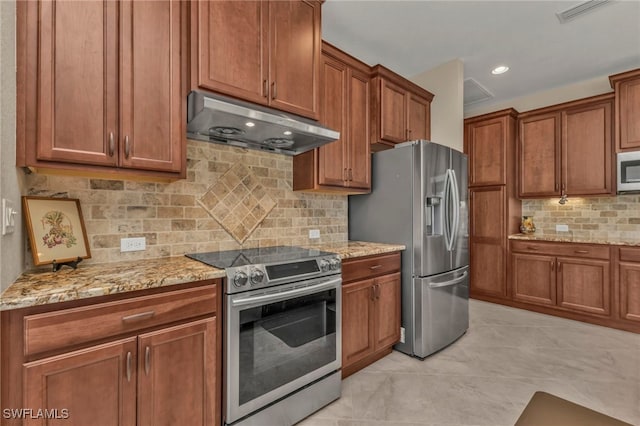 kitchen with light stone countertops, backsplash, light tile patterned floors, and stainless steel appliances