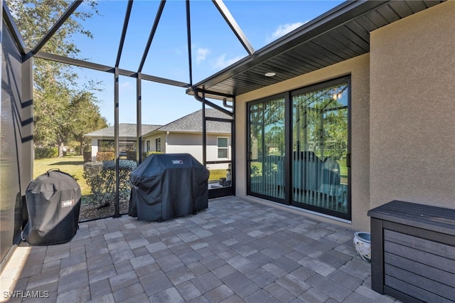 view of patio with glass enclosure and a grill