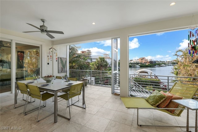 sunroom featuring ceiling fan and a water view