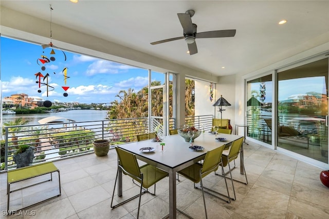 sunroom / solarium featuring ceiling fan and a water view