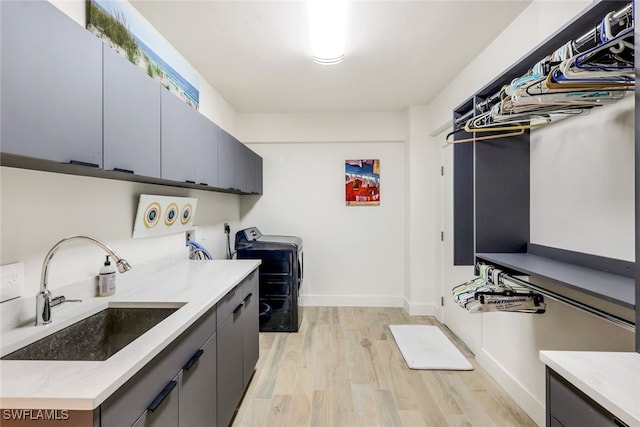 laundry area featuring cabinets, sink, light hardwood / wood-style flooring, and washing machine and dryer