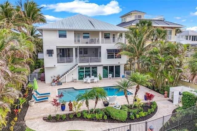 back of property with a fenced in pool and a patio