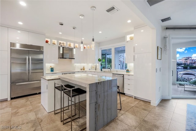 kitchen featuring hanging light fixtures, white cabinets, a center island, a breakfast bar, and stainless steel appliances