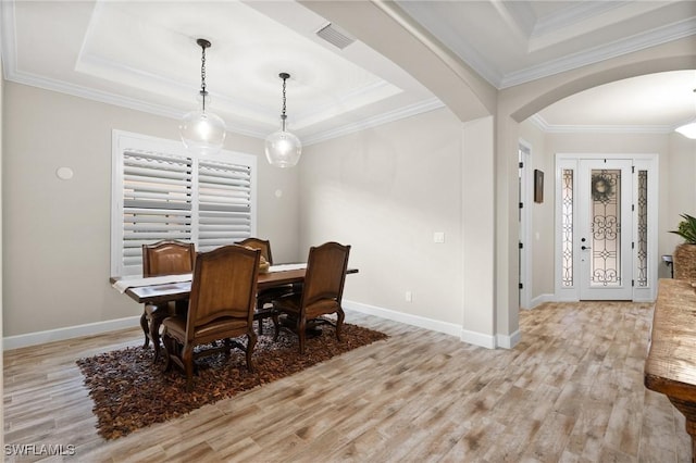 dining space featuring visible vents, arched walkways, baseboards, light wood finished floors, and a tray ceiling
