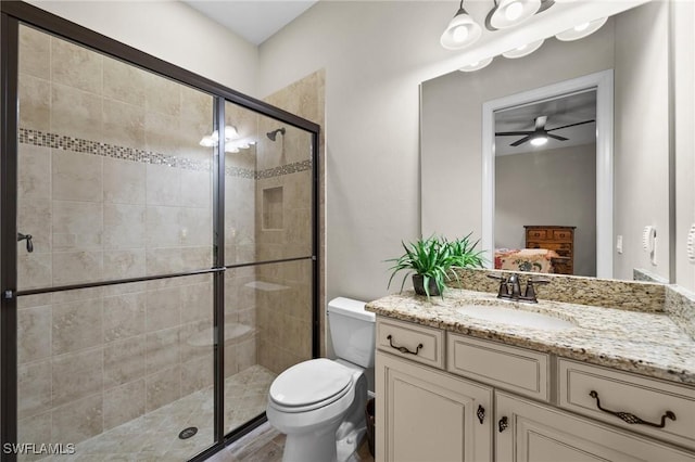 ensuite bathroom with vanity, toilet, ensuite bathroom, a shower stall, and a ceiling fan