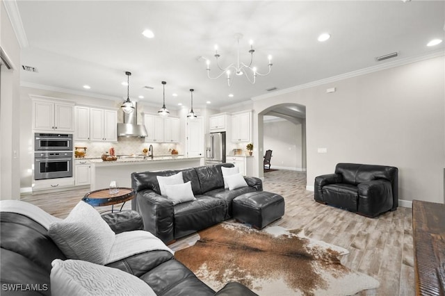 living area featuring arched walkways, a notable chandelier, recessed lighting, and light wood finished floors