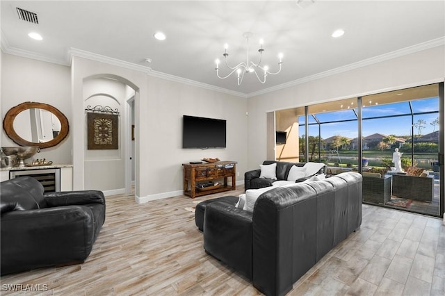 living room featuring visible vents, arched walkways, an inviting chandelier, ornamental molding, and light wood-style flooring