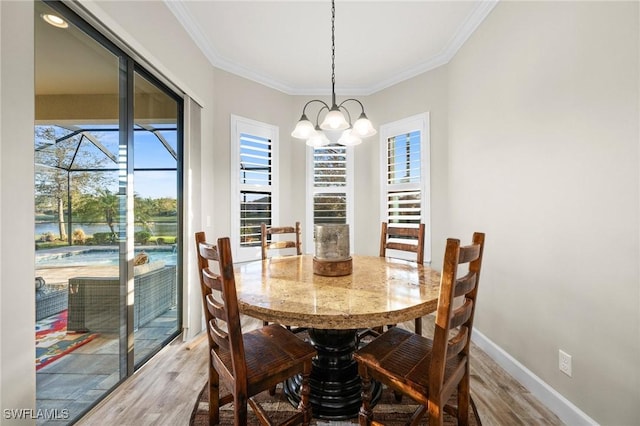 dining space with baseboards, ornamental molding, wood finished floors, and a chandelier