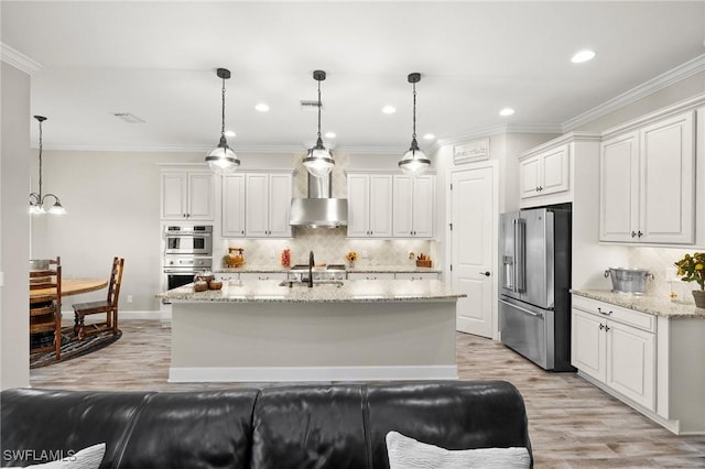 kitchen featuring wall chimney range hood, white cabinetry, appliances with stainless steel finishes, and light wood finished floors