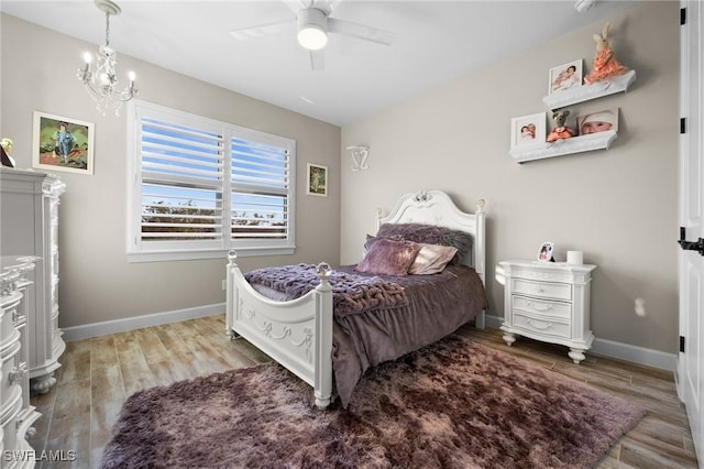 bedroom with baseboards, ceiling fan with notable chandelier, and light wood-type flooring
