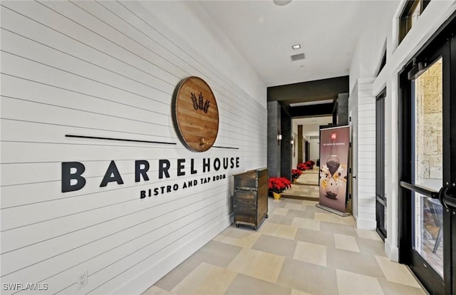 hallway with wood walls, a healthy amount of sunlight, and light floors