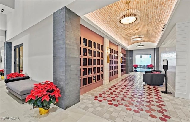 interior space with brick ceiling, a tray ceiling, vaulted ceiling, and tile patterned floors