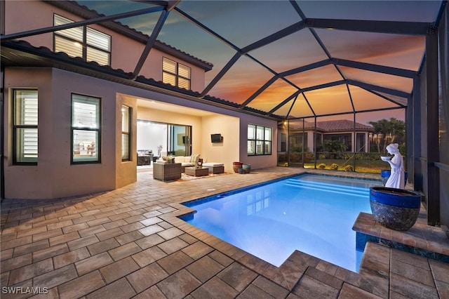8750 Cavano St E, Naples, FL 34119 - pool at dusk featuring an outdoor pool, an outdoor living space, a patio, and glass enclosure