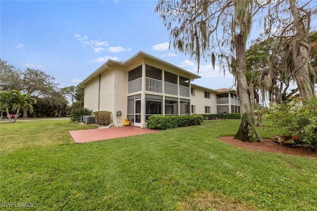 back of property featuring a sunroom, a yard, central AC, and a patio area