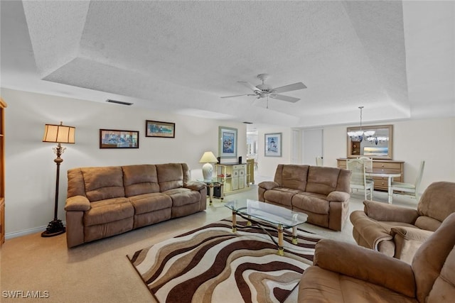 carpeted living room with a raised ceiling, ceiling fan with notable chandelier, and a textured ceiling