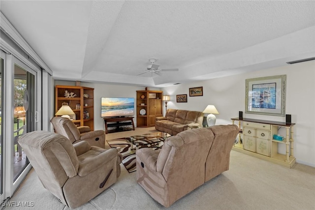 living room with ceiling fan, a raised ceiling, light carpet, and a textured ceiling