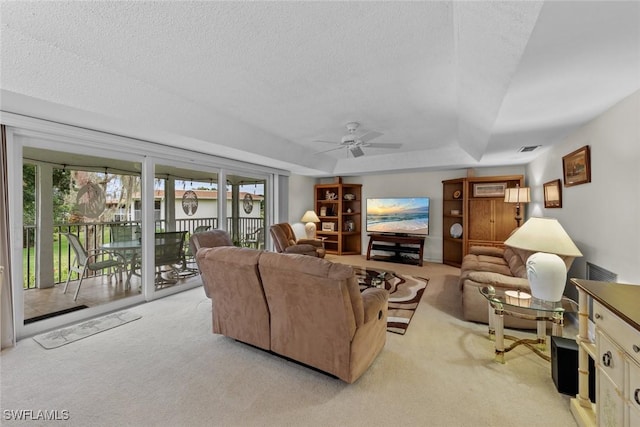 carpeted living room with ceiling fan, a raised ceiling, and a textured ceiling