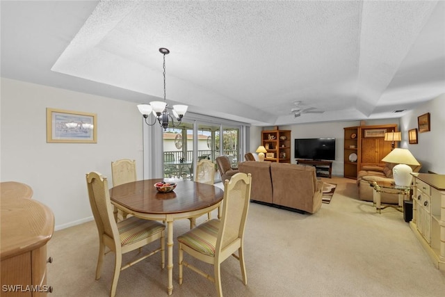 carpeted dining room with a tray ceiling, ceiling fan with notable chandelier, and a textured ceiling