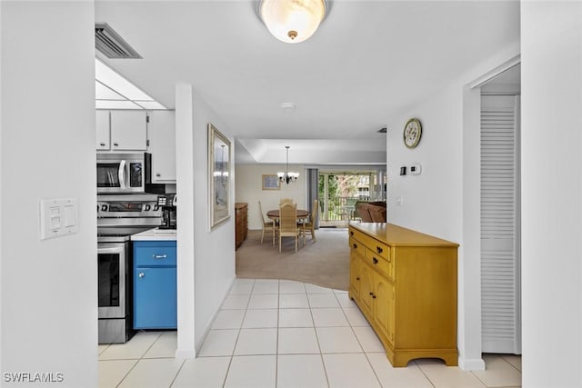 kitchen with decorative light fixtures, white cabinetry, light colored carpet, stainless steel appliances, and an inviting chandelier