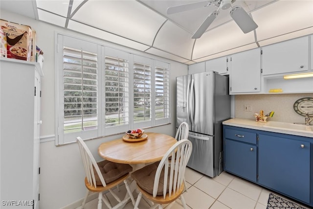 kitchen featuring sink, light tile patterned floors, blue cabinetry, backsplash, and stainless steel fridge with ice dispenser