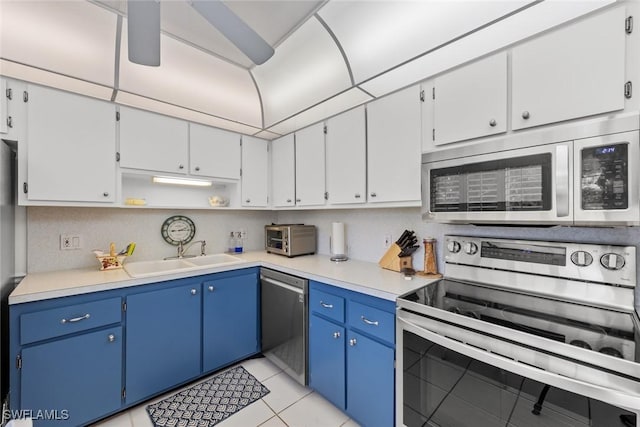 kitchen with sink, stainless steel appliances, blue cabinets, white cabinets, and light tile patterned flooring