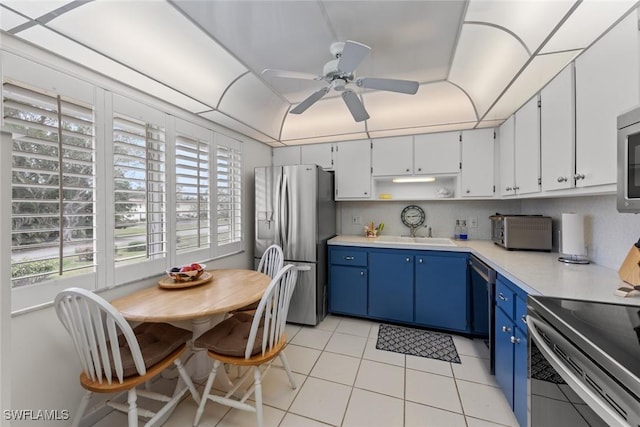 kitchen with blue cabinetry, light tile patterned floors, appliances with stainless steel finishes, ceiling fan, and white cabinets