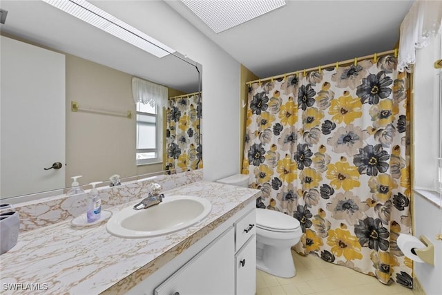 bathroom featuring a skylight, vanity, a shower with shower curtain, and toilet