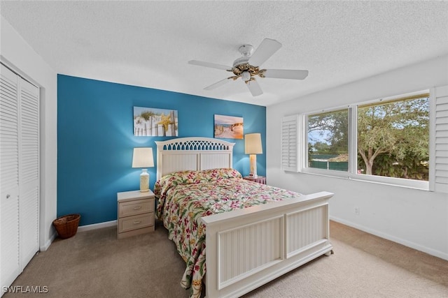 carpeted bedroom featuring ceiling fan, a closet, and a textured ceiling