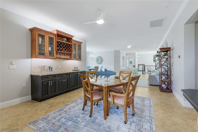 dining space with crown molding, light tile patterned floors, bar area, and ceiling fan