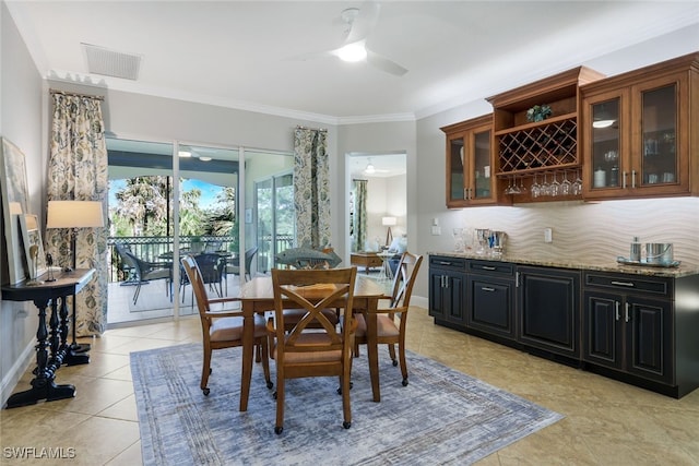 tiled dining space featuring bar, ornamental molding, and ceiling fan