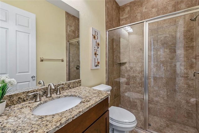 bathroom featuring vanity, toilet, and a shower with door