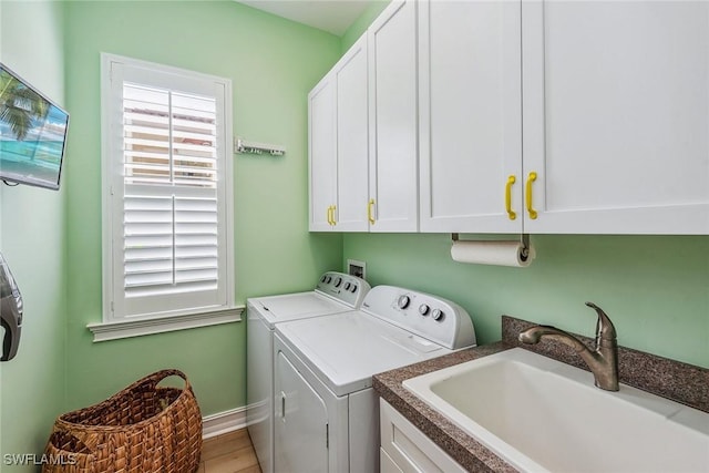 clothes washing area with cabinets, washing machine and clothes dryer, and sink