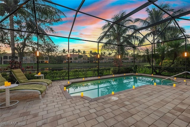 pool at dusk featuring a patio and glass enclosure