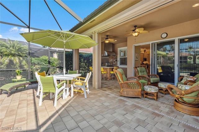 view of patio with ceiling fan and glass enclosure