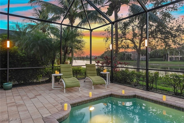 pool at dusk with a patio area, a lanai, and a water view