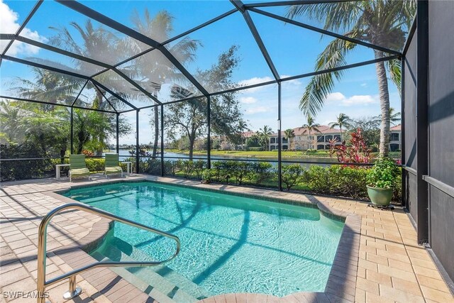 view of swimming pool featuring glass enclosure, a water view, and a patio