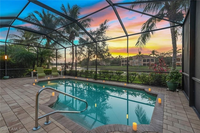 pool at dusk featuring a patio area and glass enclosure