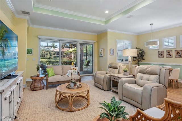 living room featuring light wood-type flooring, ornamental molding, and a tray ceiling