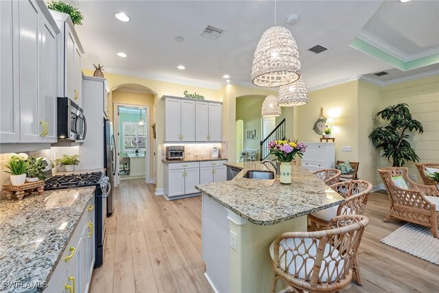 kitchen featuring a kitchen island with sink, a kitchen breakfast bar, sink, decorative light fixtures, and stainless steel appliances