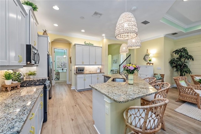 kitchen featuring sink, a kitchen island with sink, hanging light fixtures, stainless steel appliances, and a kitchen breakfast bar