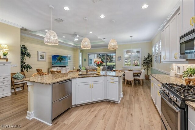 kitchen featuring pendant lighting, white cabinetry, a kitchen island with sink, and appliances with stainless steel finishes