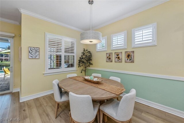 dining room featuring crown molding, light hardwood / wood-style floors, and a healthy amount of sunlight