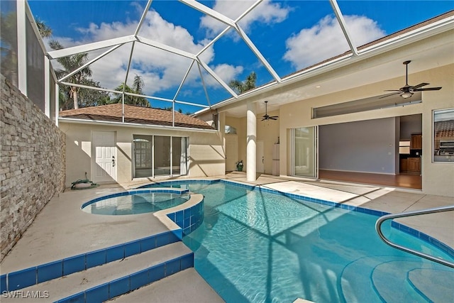 view of swimming pool with ceiling fan, a patio area, glass enclosure, and an in ground hot tub