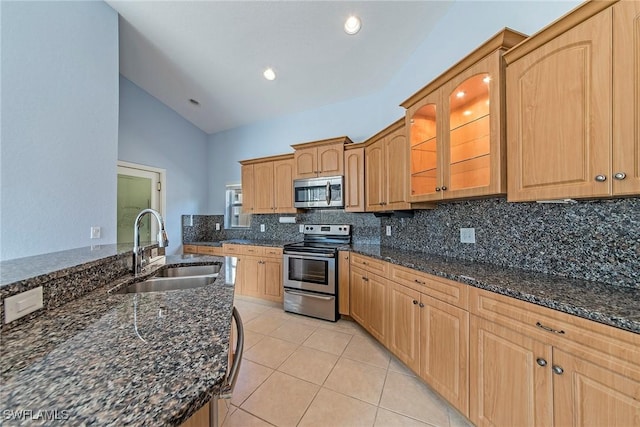 kitchen with sink, dark stone countertops, decorative backsplash, light tile patterned floors, and stainless steel appliances