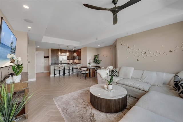 living room featuring a ceiling fan, recessed lighting, a raised ceiling, and baseboards