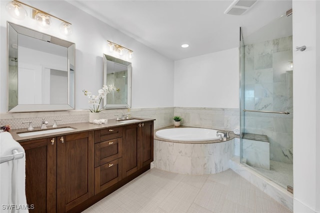 bathroom featuring a garden tub, a shower with shower door, double vanity, and tile patterned flooring