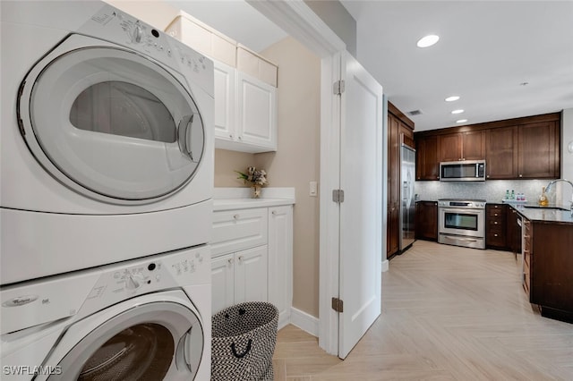 laundry room featuring sink, light parquet floors, and stacked washer / dryer