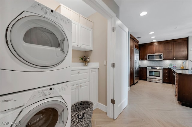 laundry area featuring stacked washer / drying machine, recessed lighting, and baseboards