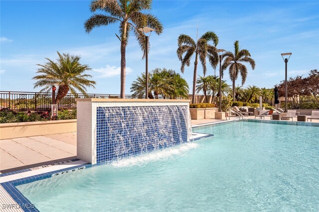 view of swimming pool with pool water feature and a patio area