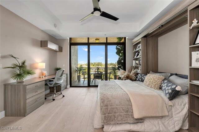 bedroom with built in desk, a wall of windows, access to exterior, ceiling fan, and light hardwood / wood-style floors